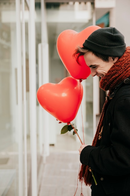 Free photo cheerful man with balloons and roses