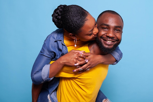 Free photo cheerful man and woman having fun with piggyback ride in studio. boyfriend carrying girlfriend and having romantic moment together, flirting. playful people in relationship bonding.