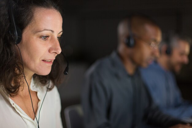 Cheerful mature call center operator looking at laptop screen