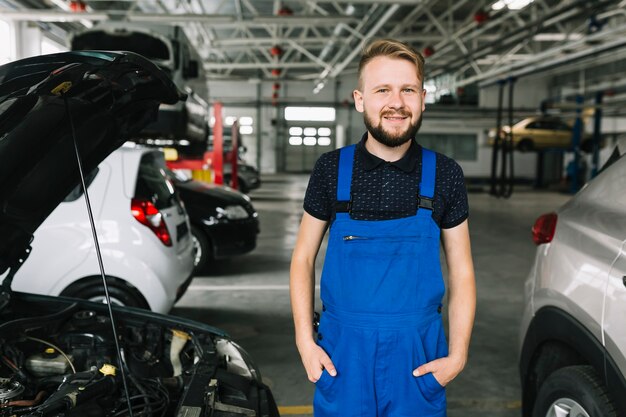 Cheerful mechanic standing near cars