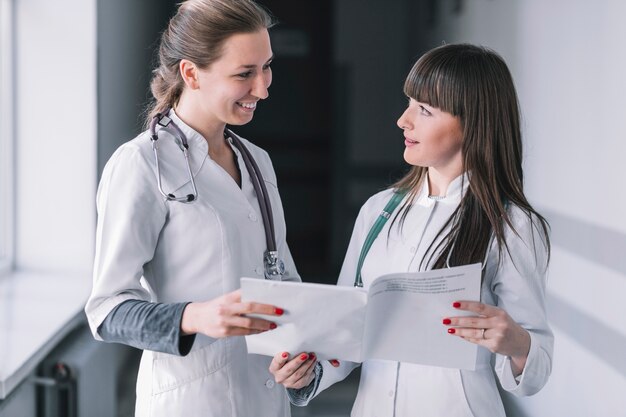 Cheerful medic women with papers in clinic