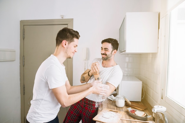 Cheerful men playing while making breakfast