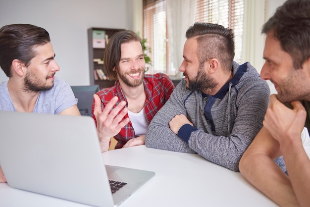 Free photo cheerful men sitting in front of the laptop