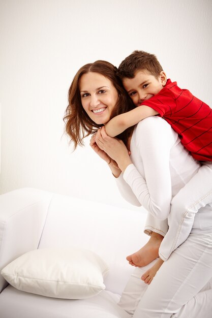 Cheerful mother carrying little boy on her back