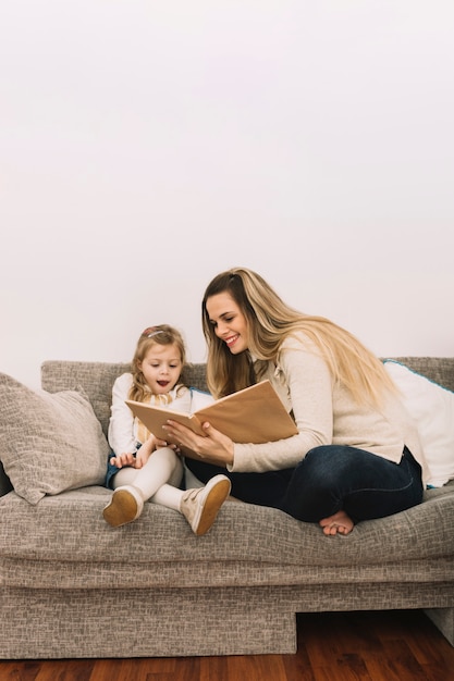 Cheerful mother reading book to daughter