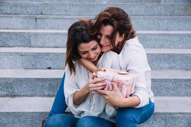 Cheerful mother receiving gift from woman