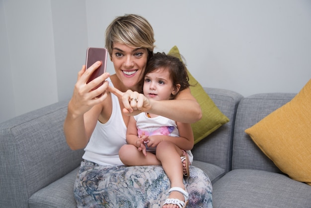 Free photo cheerful mother taking selfie with daughter