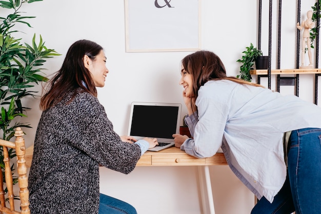 Cheerful multiethnic women at laptop