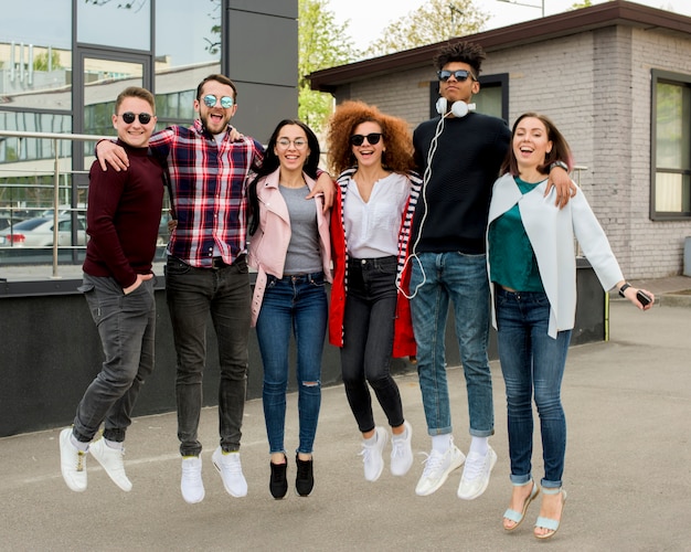 Free photo cheerful multiracial group of people jumping together on street