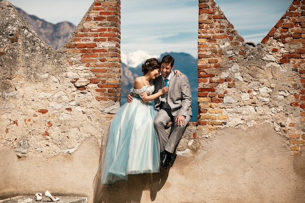 Cheerful newlyweds pose on the ruins of old fortress in the sunny day