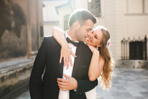 Cheerful newlyweds in sunlight on street