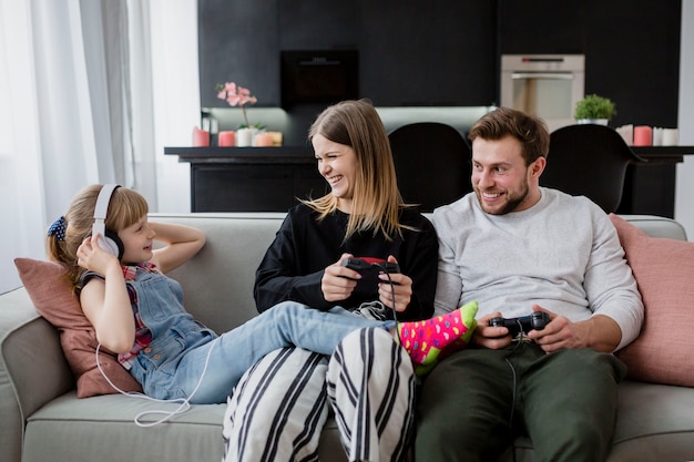 Cheerful parents playing video games near daughter