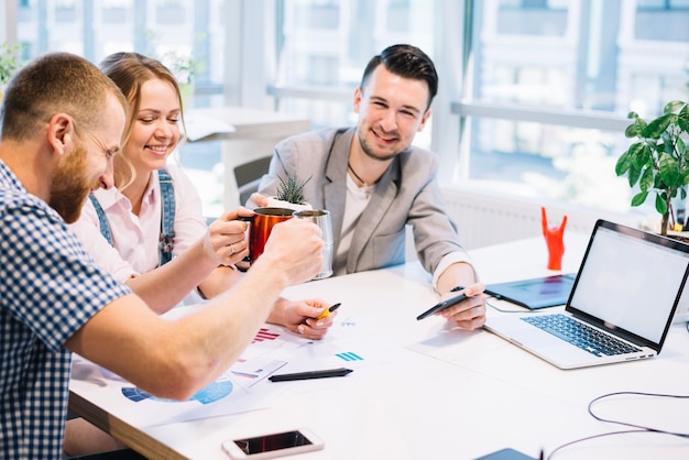 Free Photo cheerful people clinking cups while working