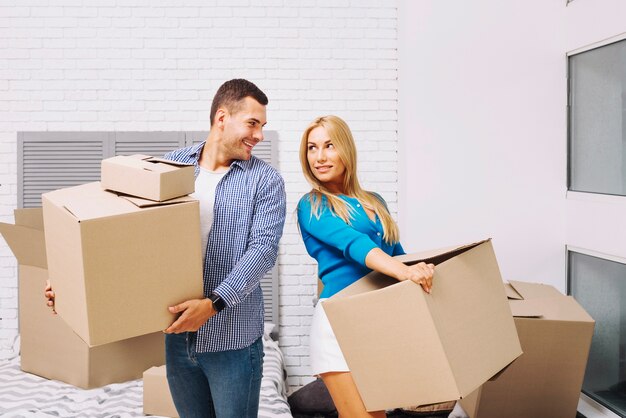 Cheerful people with boxes in new house