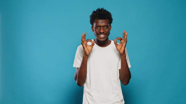 Cheerful person doing okay symbol with hands. Young man showing sign with palms and fingers expressing approval and agreement with gesture. Casual adult with positive attitude smiling