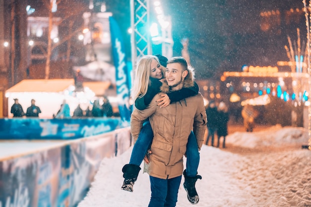 Cheerful and playful couple in warm winter outfits are fooling around