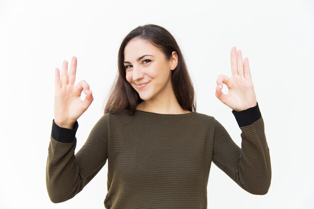 Cheerful positive beautiful woman making Okay gesture