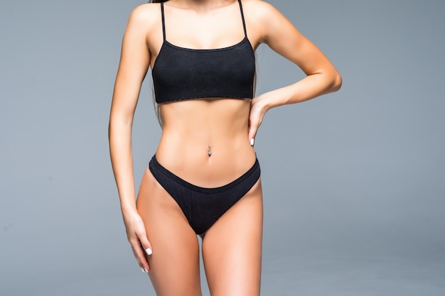 Cheerful positive sexy fit woman in lingerie pointing to her slim belly.woman showing her flat stomach, ideal waist, woman boasting about her weight. isolated white wall, fitness, sport