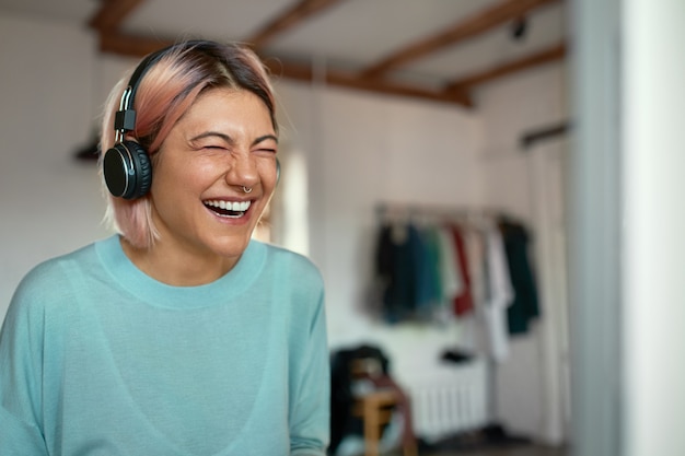 Free Photo cheerful positive young female blogger with nose ring laughing while recording podcast, using headset.