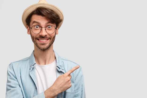 Cheerful prosperous man farmer in casual domestic clothes, indicates aside as shows his beautiful garden with many plants, feels proud, being hard working, has happy expression