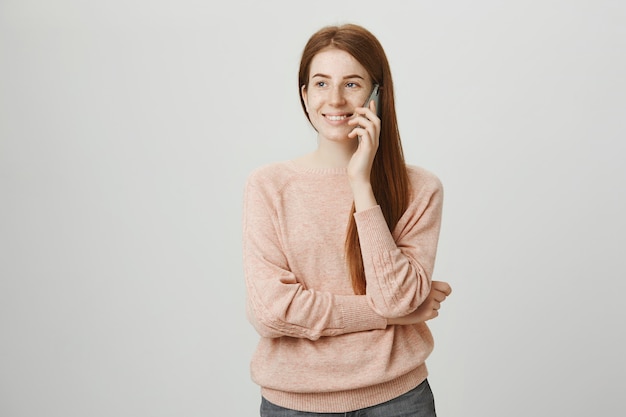 Cheerful redhead girl having mobile conversation, smiling