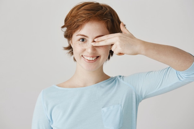 Cheerful redhead girl posing against the white wall