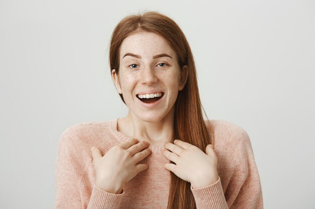 Cheerful redhead girl receive big news, smiling surprised