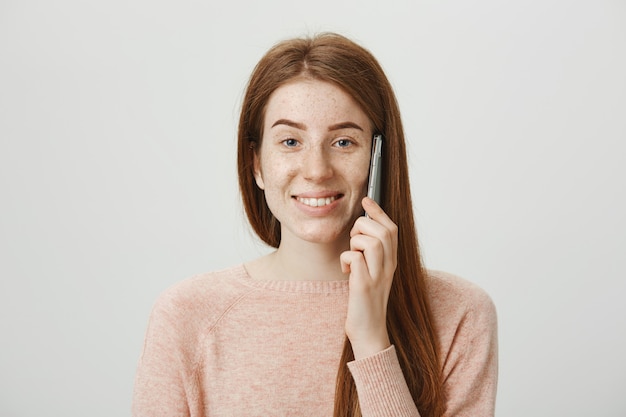 Cheerful redhead girl with freckles, smiling and talking on phone carefree