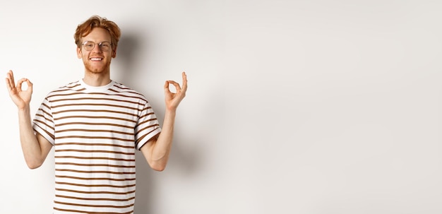 Free photo cheerful redhead man in glasses have all under control showing okay signs and smiling satisfied stan