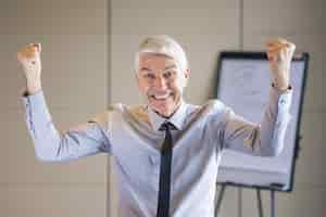 Free photo cheerful senior businessman pumping fists