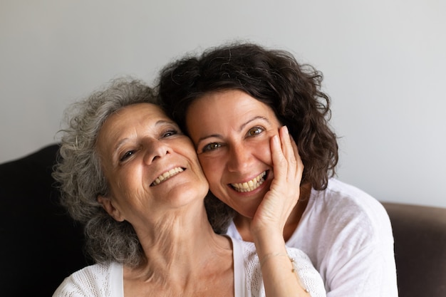 Cheerful senior mother and adult daughter posing at home