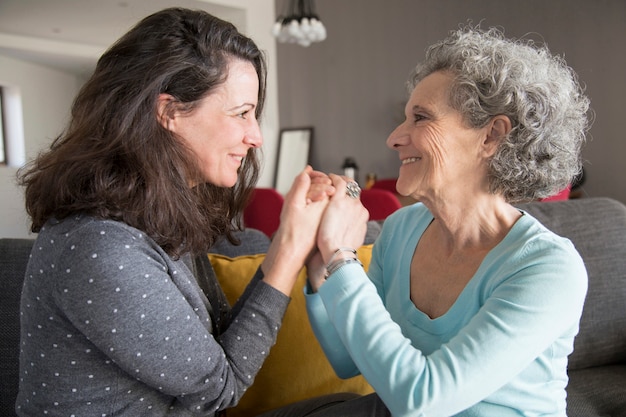 Free photo cheerful senior mother and her daughter holding hands