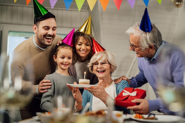 Free photo cheerful senior woman and her extended family having fun while celebrating her birthday in dining room