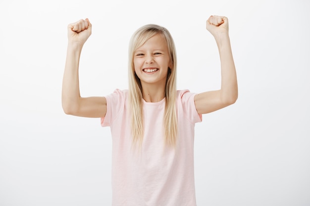 Free photo cheerful smiling little girl raise hands up, winning and triumphing