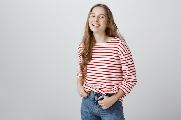 Free photo cheerful smiling teenage girl standing happy over grey wall