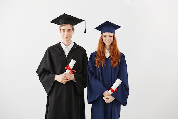 Cheerful students graduates smiling holding diplomas. 