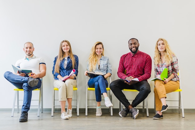 Cheerful students posing on chairs