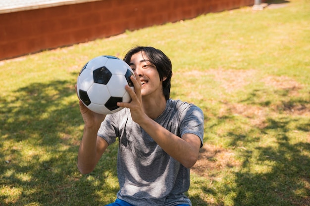 Cheerful teen Asian student catching soccer ball