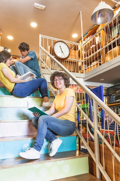 Free Photo cheerful teen girl with book sitting near friends