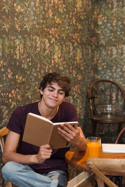 Cheerful teenager reading in cafe