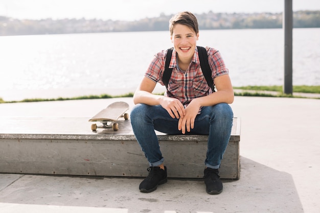 Free Photo cheerful teenager sitting on border