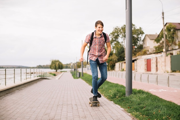 Free Photo cheerful teenager skateboarding on pavement