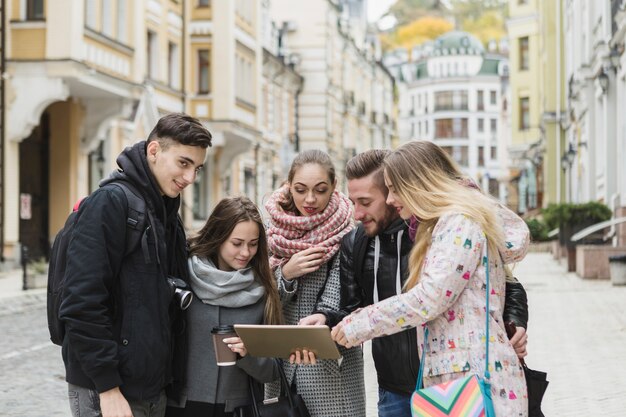 Cheerful tourists with tablet on street