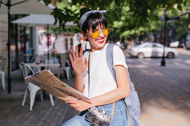 Cheerful trendy girl with  waving hand in silver ring and smiling, looking away