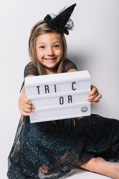 Free photo cheerful witch showing board with writing