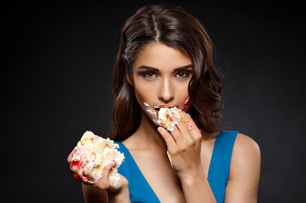 Cheerful woman in blue dress eating piece of cake