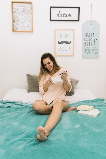 Cheerful woman having breakfast and reading book