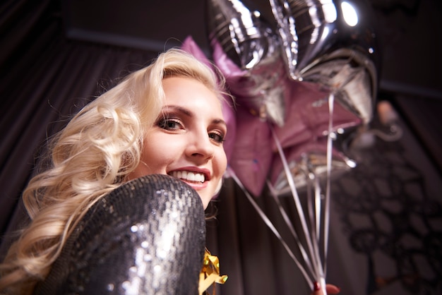 Free photo cheerful woman holding bunch of balloon at night club