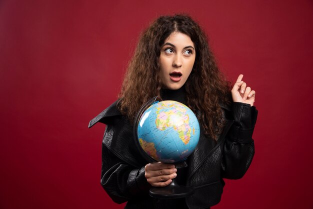 Cheerful woman holding globe.