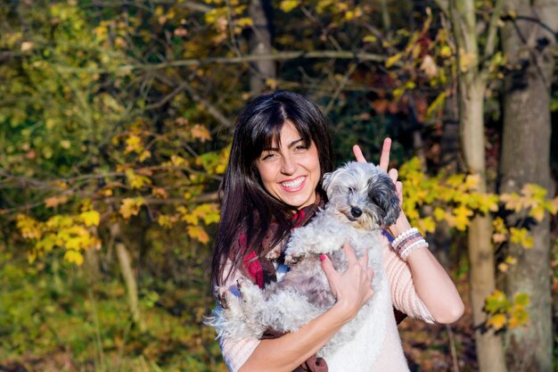 Cheerful woman holding her dog outdoors